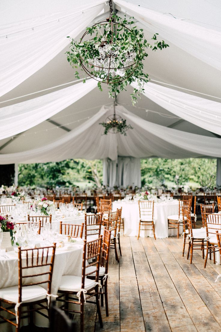 a large tent with tables and chairs set up for a wedding or reception in the woods