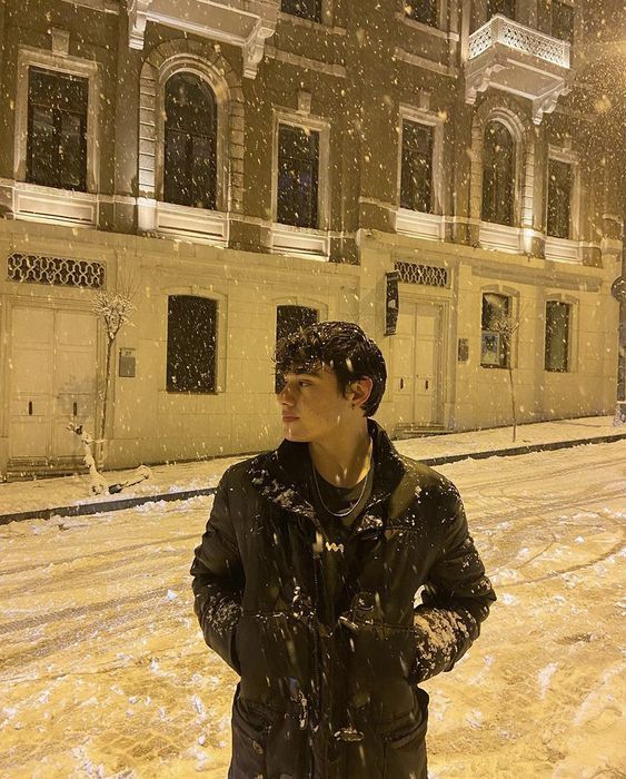 a man standing in the snow next to a building