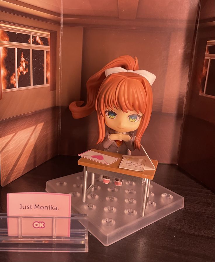 a plastic doll sitting on top of a table next to a box with donuts in it