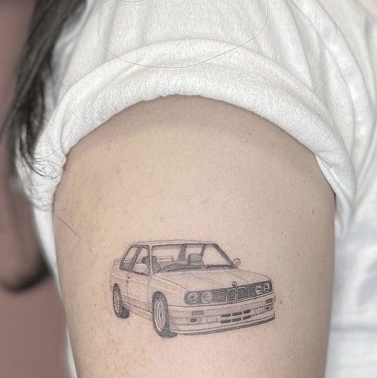 a woman's arm with a small tattoo of a car on the back of her shoulder