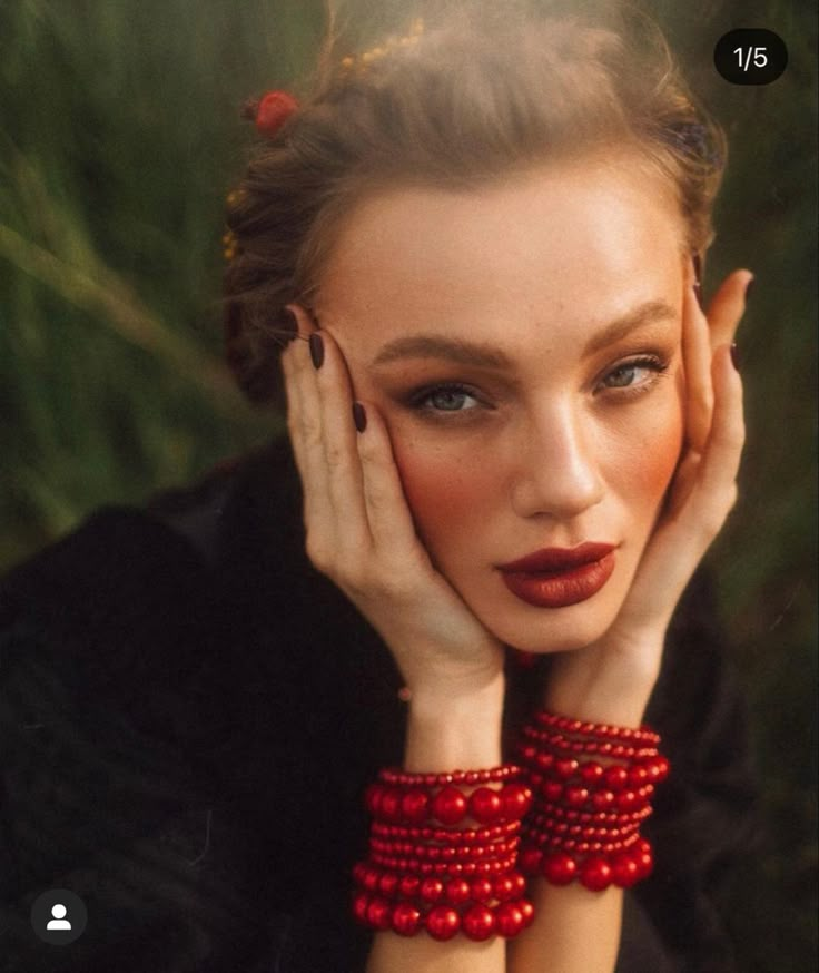 a woman with her hands on her face wearing red bracelets and holding her hand near her face