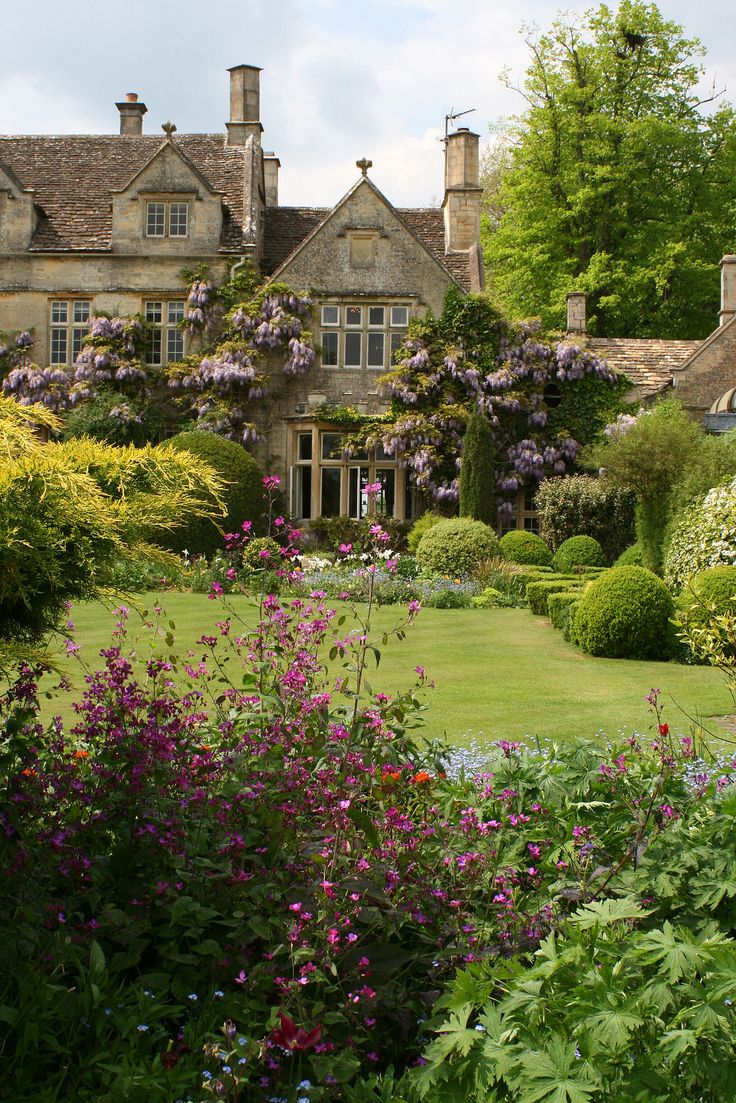 a large house surrounded by lush green grass and flowers