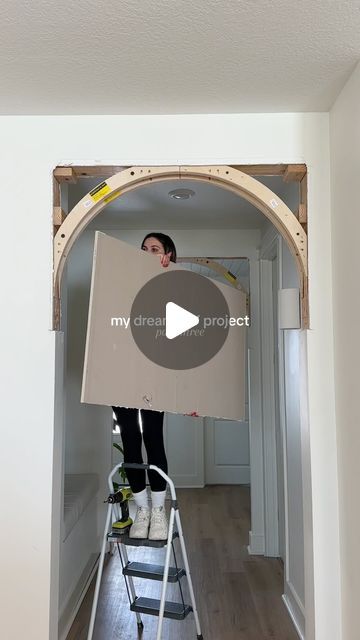 a woman standing on a ladder holding a box