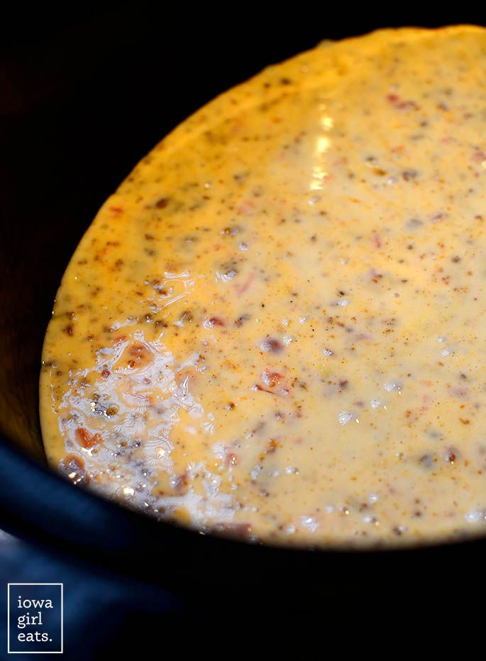 a crock pot filled with cheese sauce on top of a stove