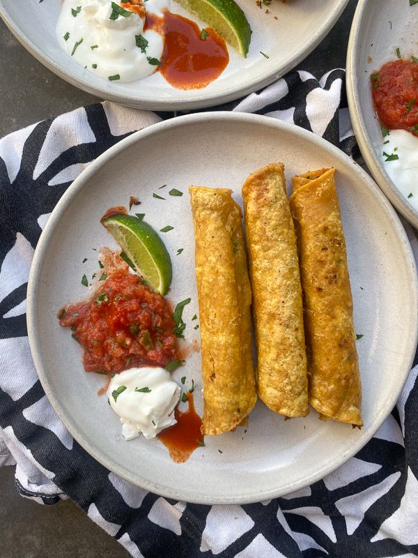 two white plates topped with food on top of a black and white table cloth next to each other