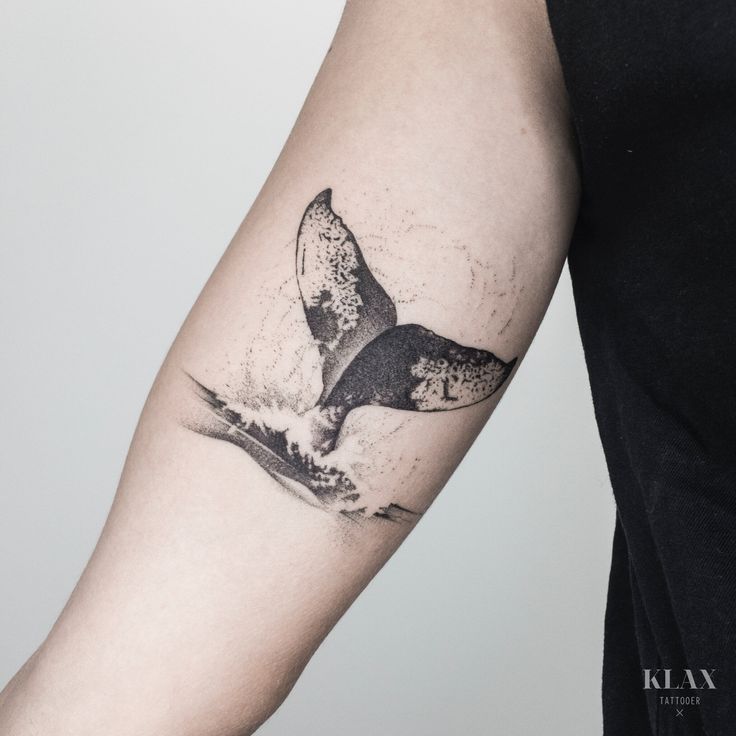 a whale tail tattoo on the left arm