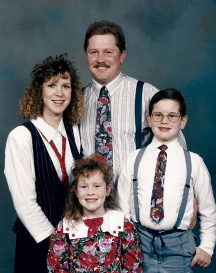 the family is posing for a photo in their dress clothes and ties, with one child smiling at the camera