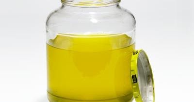 a glass jar filled with yellow liquid next to a measuring tape on a white surface