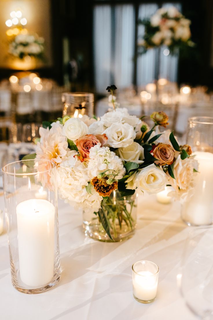 a table with candles and flowers in vases sitting on it's centerpiece