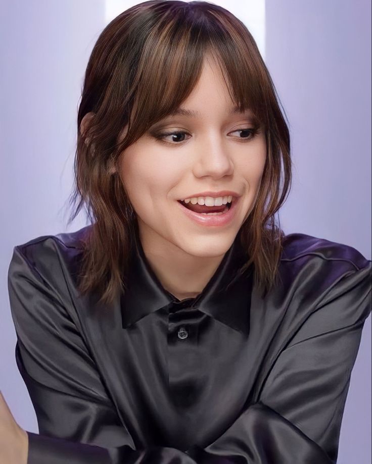 a woman with long hair wearing a black shirt and smiling at the camera while holding her arms crossed