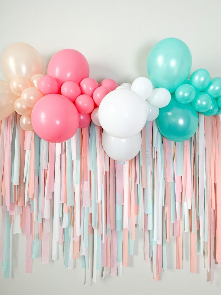 balloons, streamers and tassels are arranged on the wall for a party