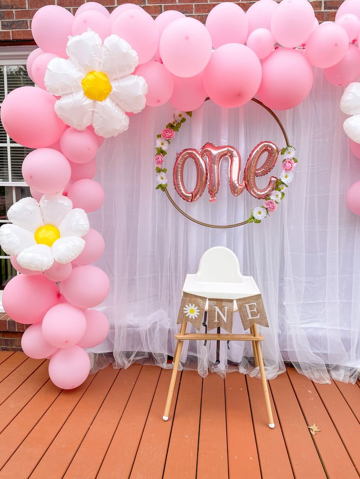 a chair sitting under a balloon arch with the word'one'in front of it