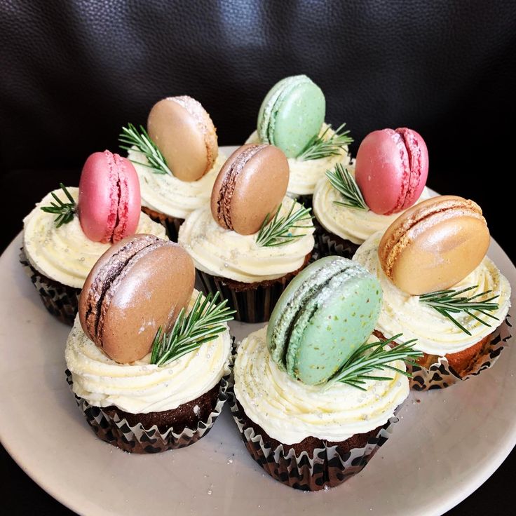 cupcakes decorated with frosting and sprigs sit on a white plate