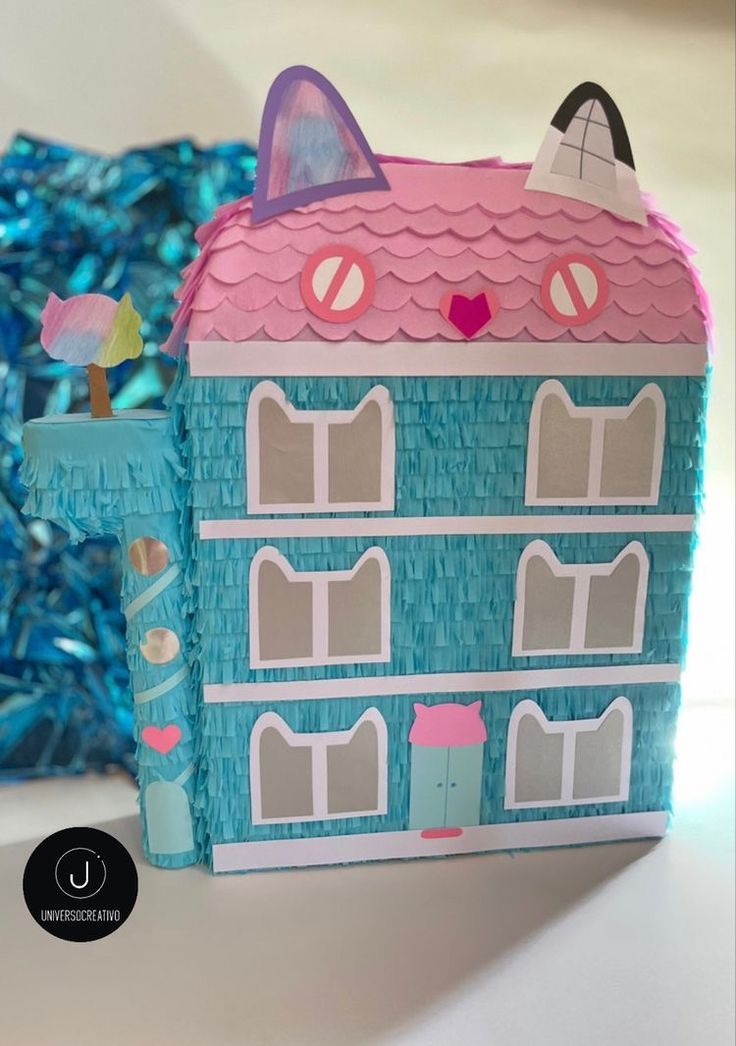 a paper doll house sitting on top of a table next to blue tinsels