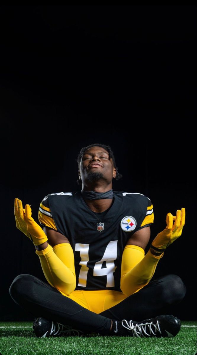 a football player sitting on the ground with his hands in the air and eyes closed