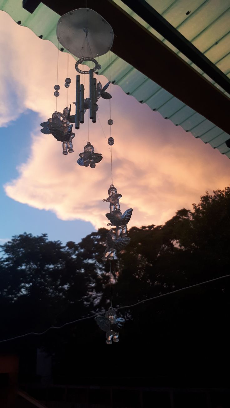 the sun is setting behind an umbrella with chandeliers hanging from it's roof