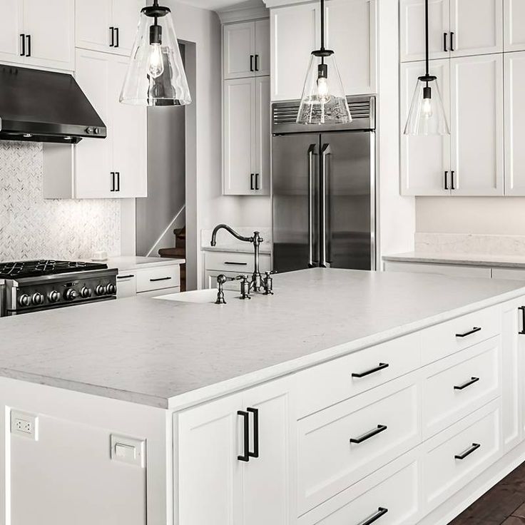 a large kitchen with white cabinets and stainless steel appliances in the center, along with marble counter tops