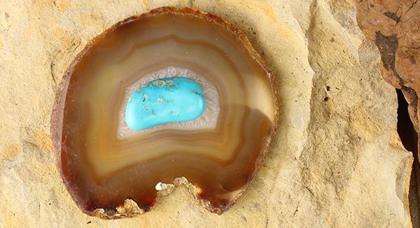 a piece of agate stone with a blue substance in it's center sitting on some rocks