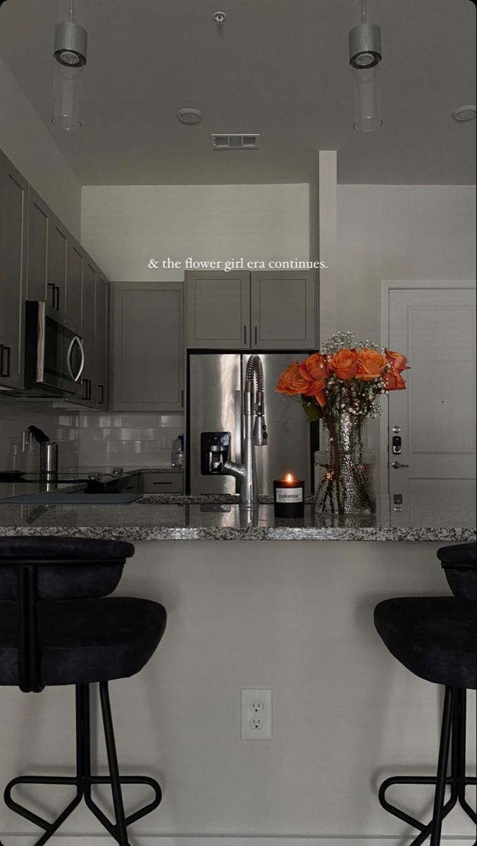 two bar stools sit in front of a kitchen counter with flowers on the island