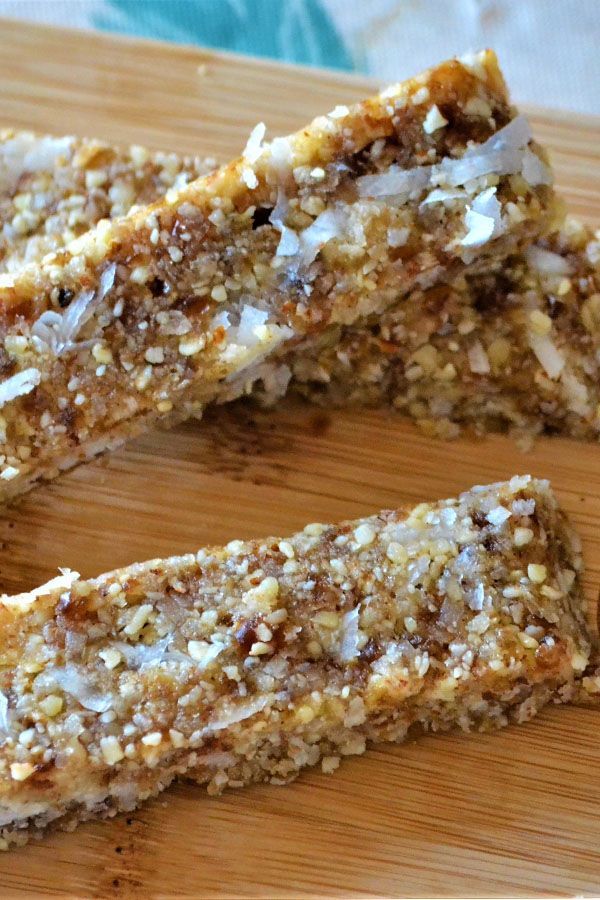 two pieces of granola bar sitting on top of a wooden cutting board next to a knife