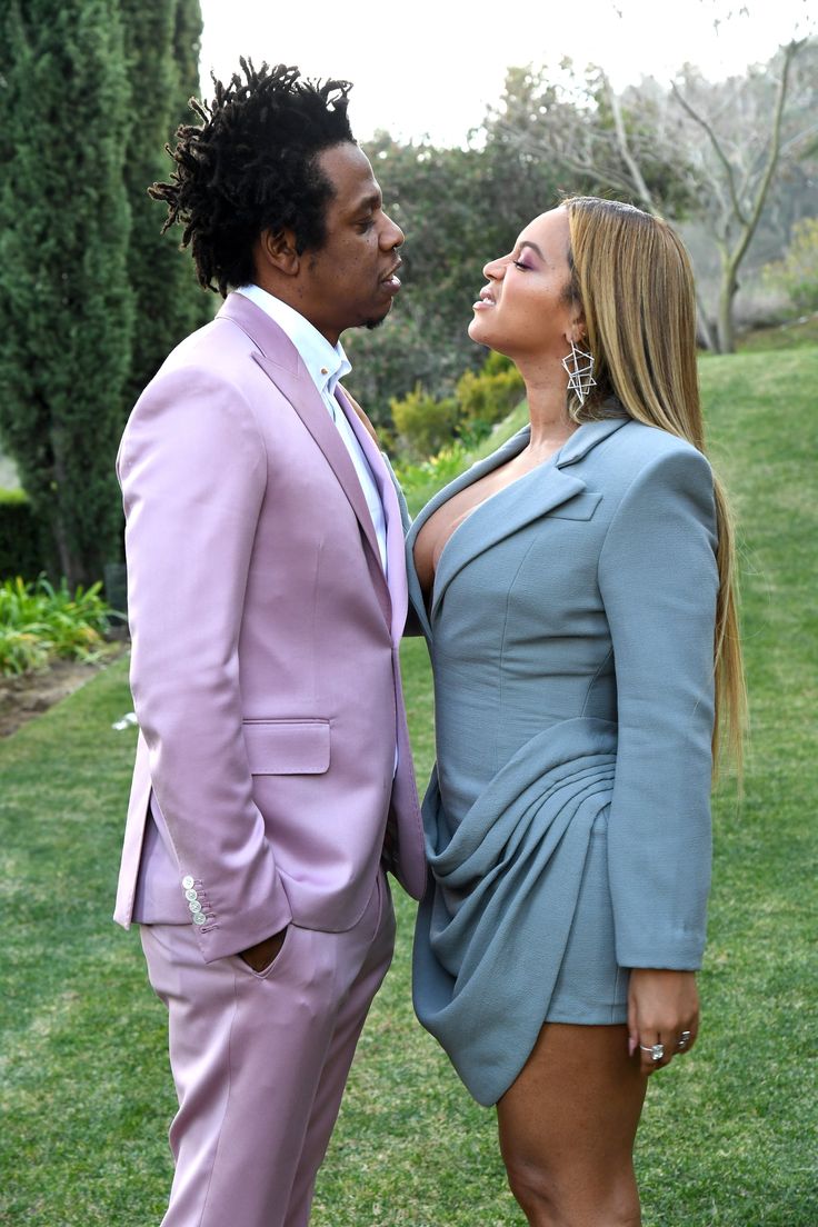 a man and woman standing next to each other on top of a lush green field