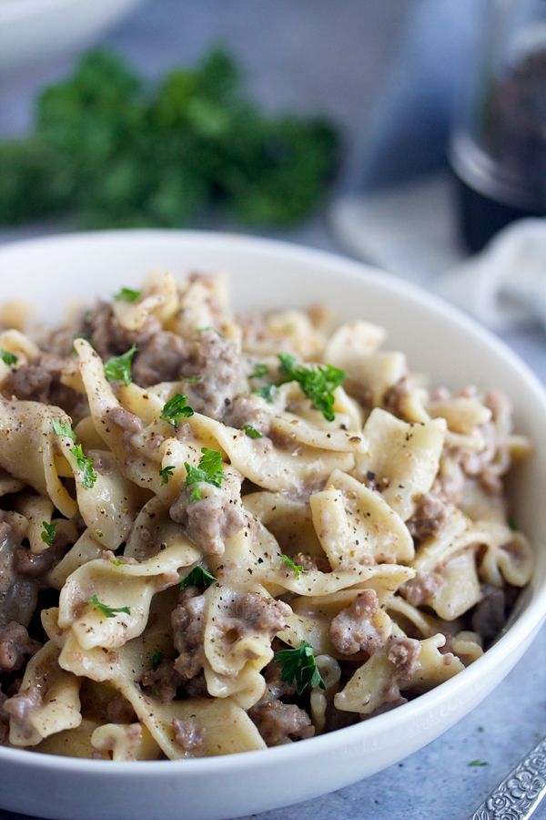 a white bowl filled with pasta and meat