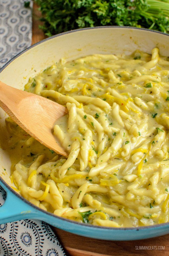 a wooden spoon in a blue pan filled with pasta