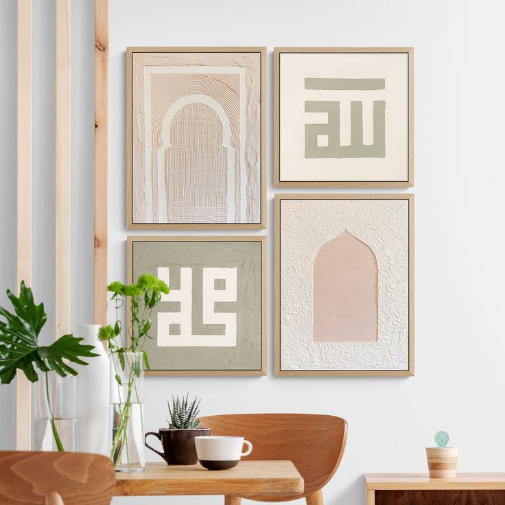 three framed art pieces hang on the wall above a table with a cup and potted plant