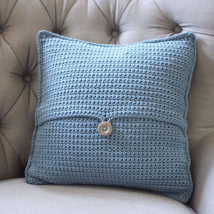 a blue crocheted pillow sitting on top of a couch