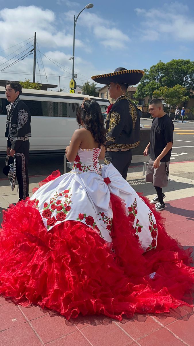 a woman in a red and white dress is walking down the street with other people