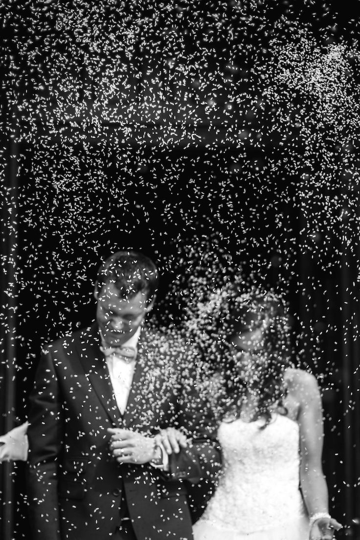 a man and woman are standing in front of confetti falling from the sky