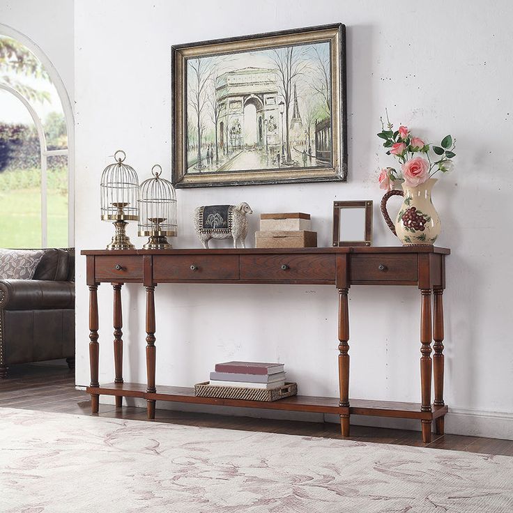 a table with flowers and books on it in front of a painting hanging on the wall