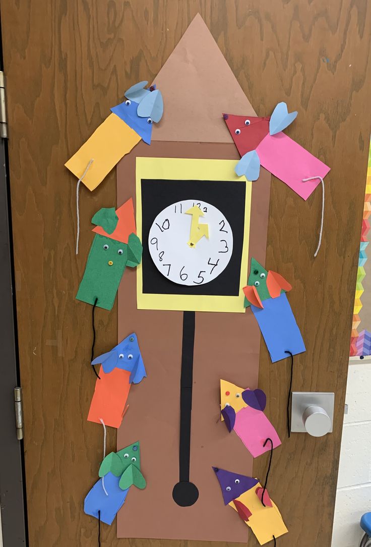 a clock made out of construction paper and cutouts on the side of a door