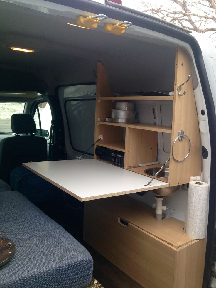 the back end of a van with a table and shelves