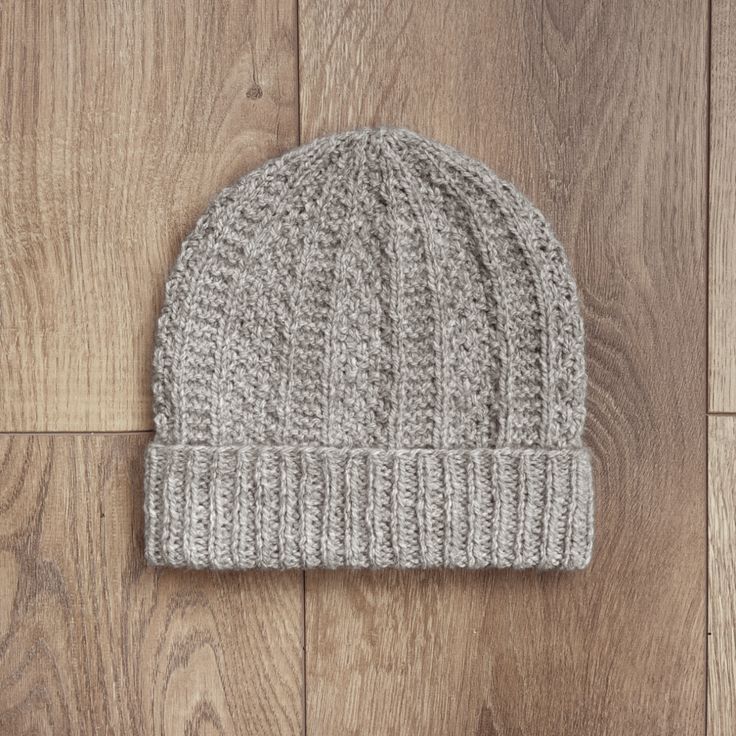 a gray knitted beanie sitting on top of a wooden floor