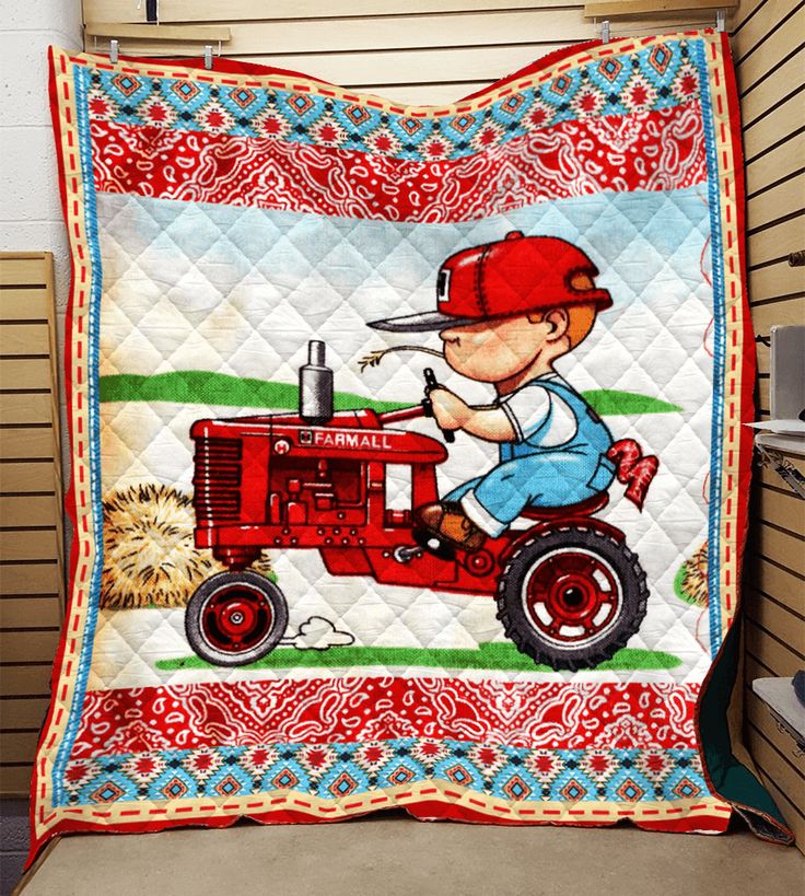 a red tractor with a little boy on it is quilted onto the side of a wall