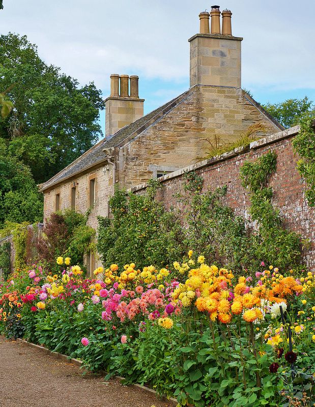 an old brick building surrounded by colorful flowers