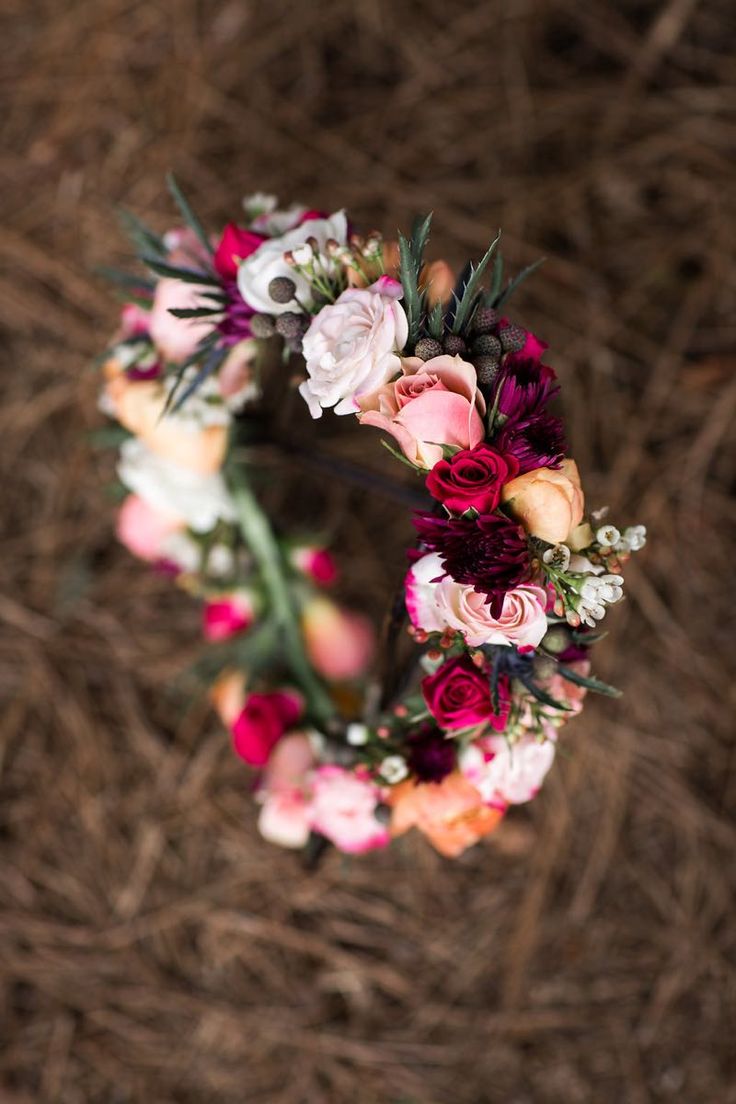 an overhead view of a floral wreath on the ground with dried grass in the background