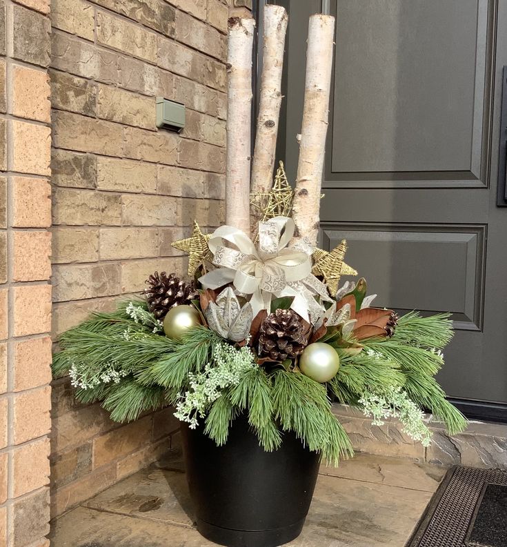 a vase filled with pine cones and greenery on top of a table next to a door