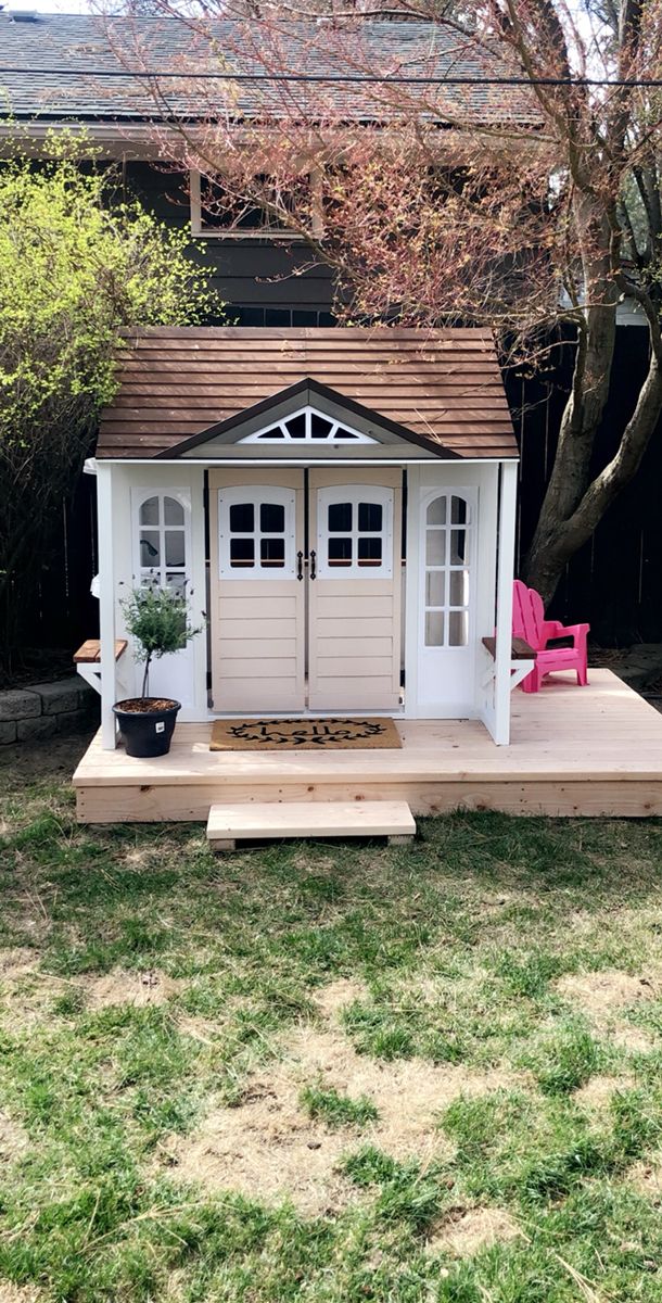 a small white shed sitting in the middle of a yard