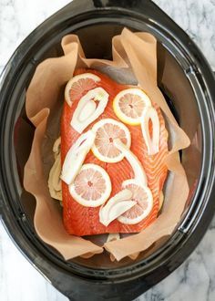 the fish is covered with sliced lemons and other ingredients in the slow cooker