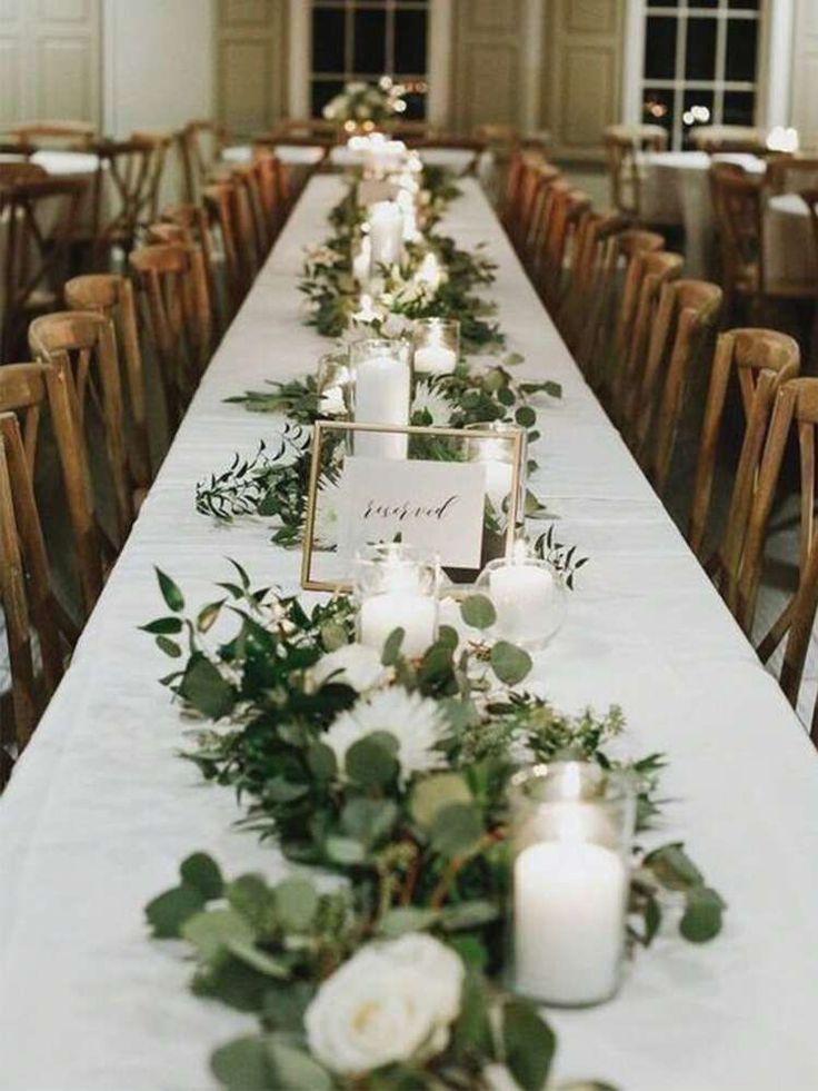 a long table with candles and greenery is set up for an elegant dinner party