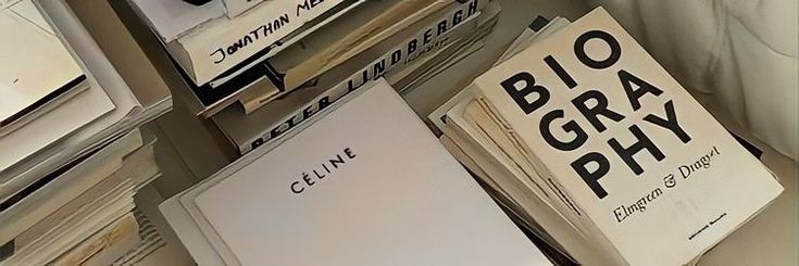 several books stacked on top of each other in front of a white wall with black lettering