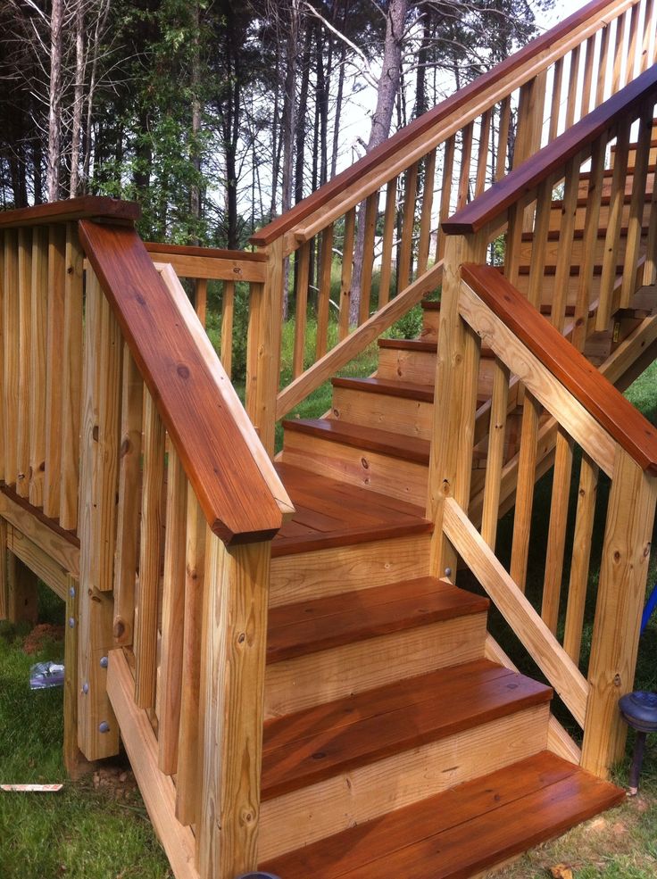 a wooden staircase with handrails in the grass