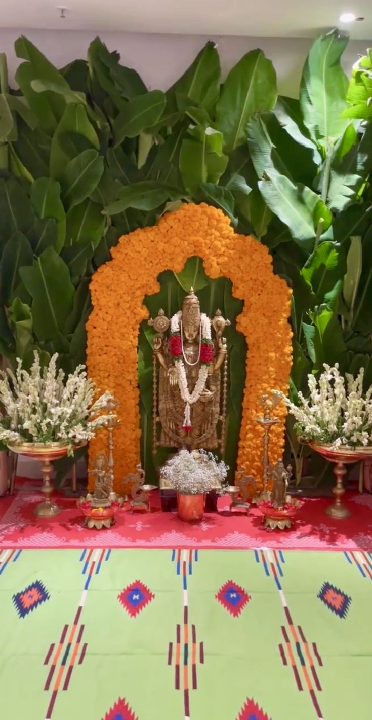 there is a small shrine with flowers on the table and plants in front of it