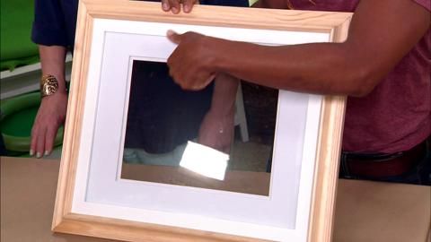 a man holding up a framed photo with his right hand and thumb on the frame