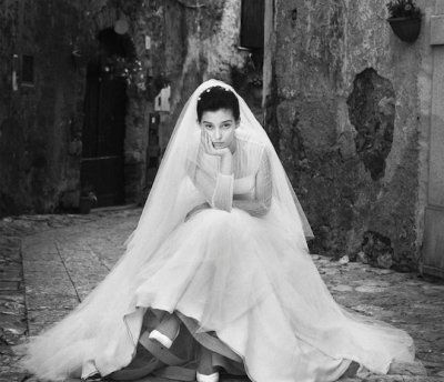 a black and white photo of a woman in a wedding dress sitting on the ground