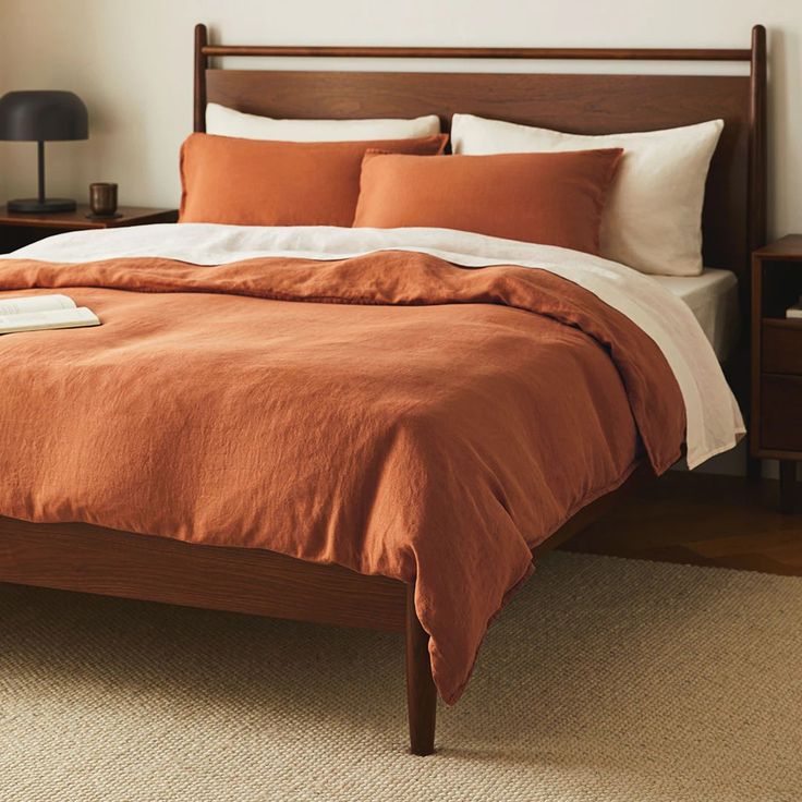 a bed with an orange comforter and two nightstands next to it in a bedroom