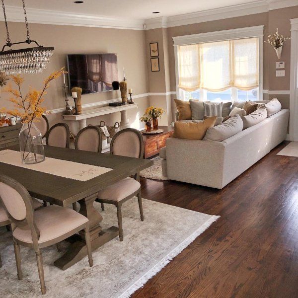 a living room and dining room with wood flooring in the center, beige furniture on the far wall