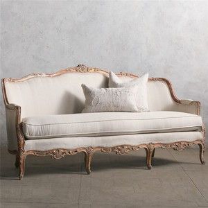 a white couch sitting on top of a wooden floor next to a wall with two pillows